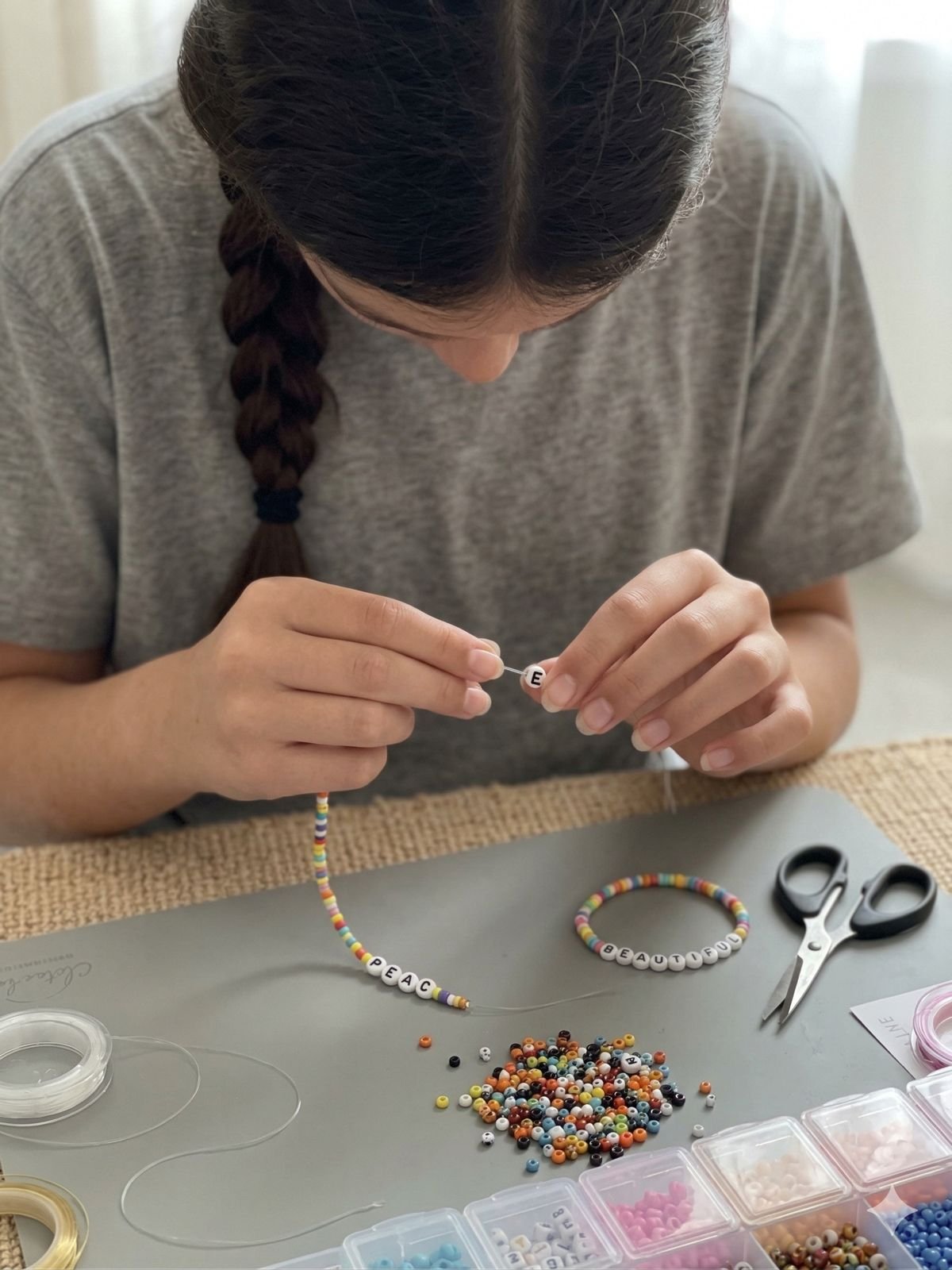 ילדה משחילה חרוזי אותיות על חוט ליצירת צמיד שם